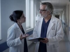 Médicos conversando em corredor de hospital